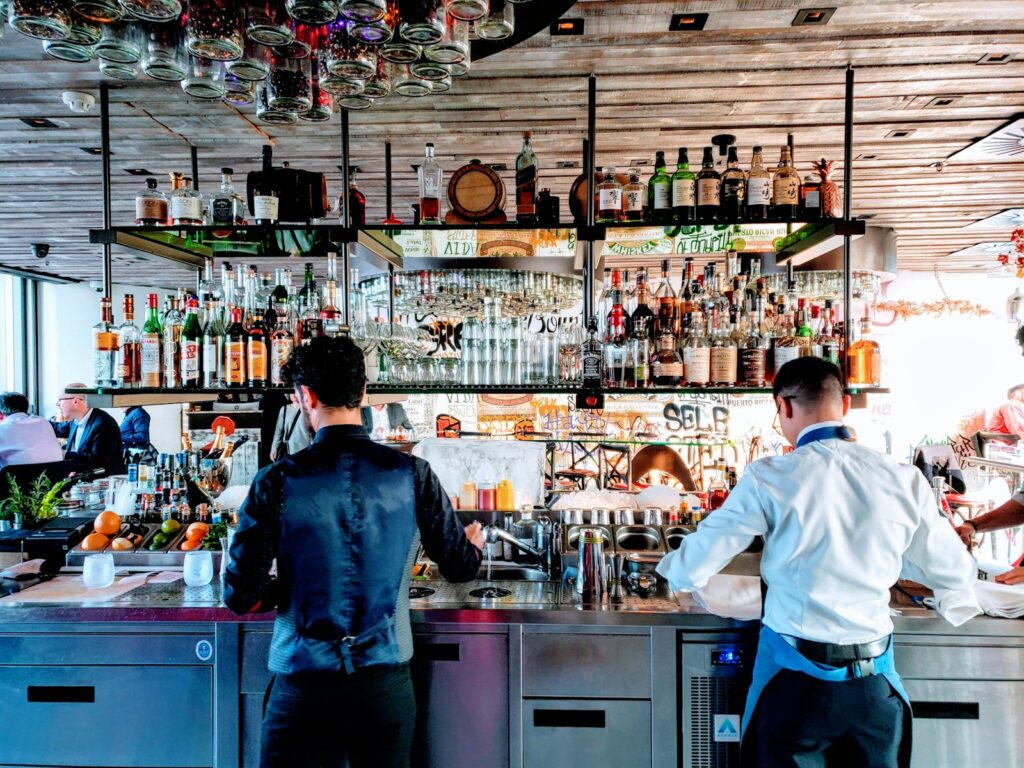 Photo by Maxwell Jayes two men standing near table inside bar